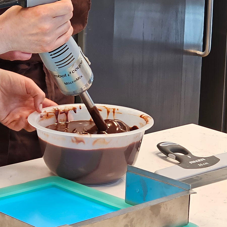 Person using an immersion blender to emulsify chocolate ganache